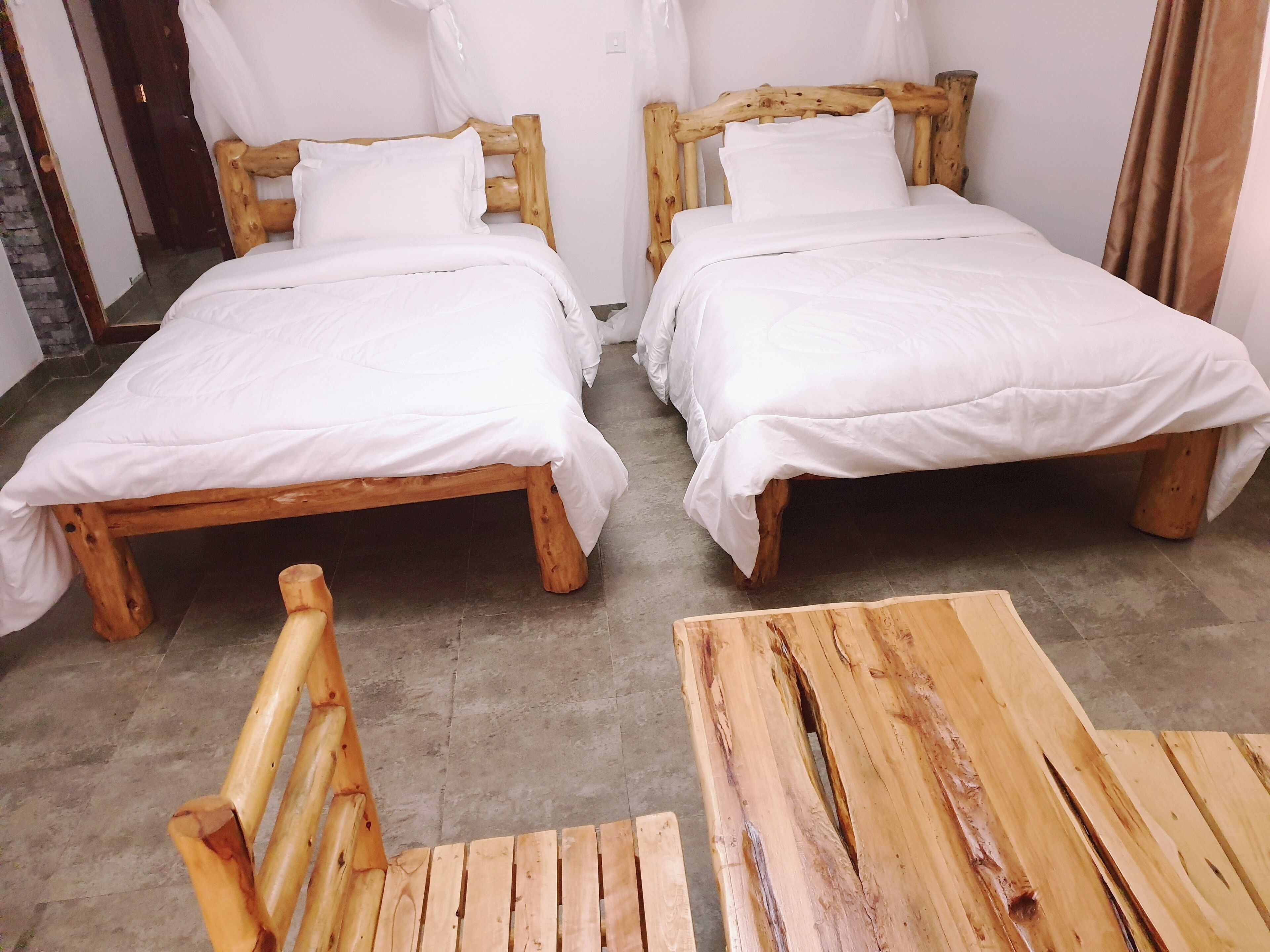 A room with two wooden beds, white bedding, and a wooden table.