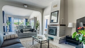 Un salon avec une cheminée, un canapé, une table basse et une vue sur l’extérieur.