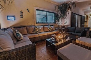 A cozy living area with a sofa, a coffee table with drinks, and a large window.