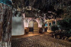 Un sentier pavé de pierres menant à un bâtiment de style traditionnel, doté de portes en arc de cercle et de grands vases.