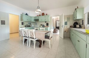 Een keuken met lichtgroene kasten, een eettafel met stoelen en een hangende lamp.