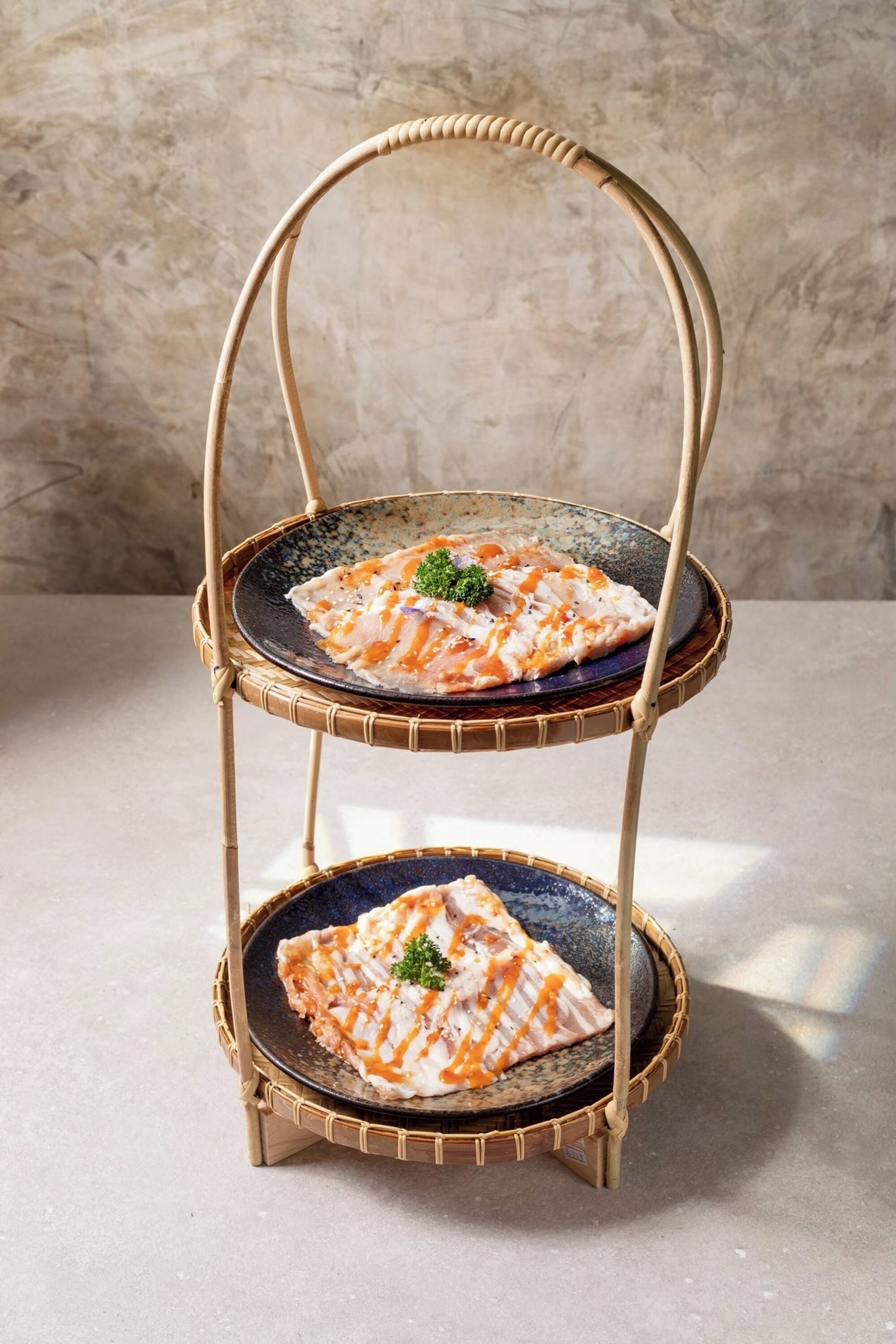 Un présentoir à trois niveaux en bambou, sur lequel sont disposés des plateaux de poisson grillé.