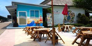 A beach-themed building with a mural, outdoor seating, and a sign for Jungle Adventure Park.
