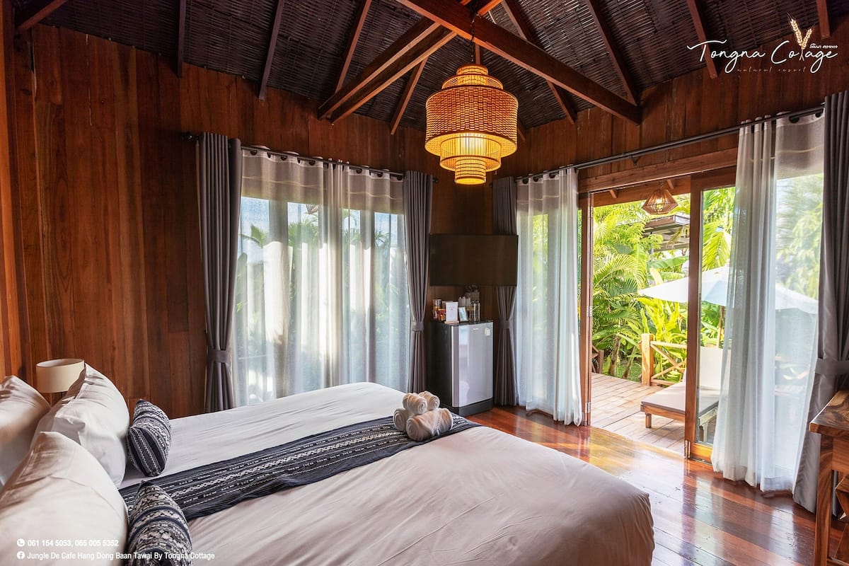 A spacious bedroom with a large bed, wooden walls, and a ceiling fan.