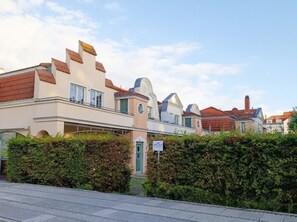 Une rangée de maisons modernes aux toits plats, avec une haie bien entretenue au premier plan.