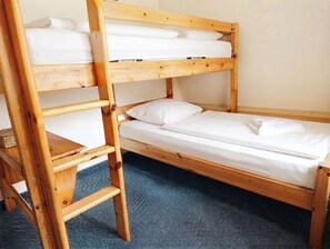 Un lit superposé avec une échelle en bois, un lit simple en dessous et une petite table.