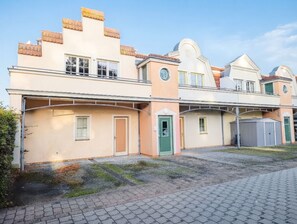 Une rangée de maisons de ville avec une allée couverte, des portes individuelles et un petit abri de jardin.
