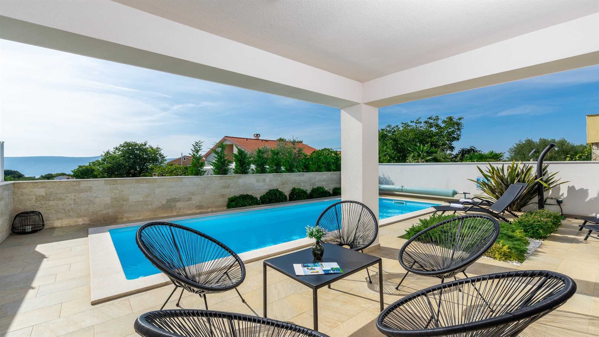 A poolside area with a view of a house and greenery.