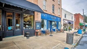 A storefront with a closed sign, outdoor seating, and a trash can.
