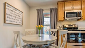 A kitchen with wooden cabinets, a microwave, an oven, and a dining table with chairs.