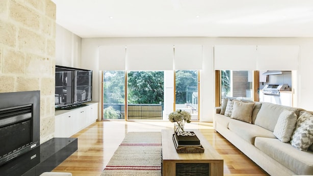 A spacious living room with a fireplace, a flat-screen TV, a sofa, and a large window offering a view of greenery. - Pet Friendly - Garden Elegance in Blairgowrie (Blairgowrie)