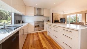 A modern kitchen with white cabinetry, a stainless steel oven, and a wooden floor. - Pet Friendly - Garden Elegance in Blairgowrie (Blairgowrie)
