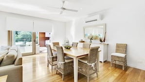 A modern dining area with a wooden table and wicker chairs, a ceiling fan, and a view of the outdoors. - Pet Friendly - Garden Elegance in Blairgowrie (Blairgowrie)
