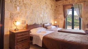 A room with two beds, stone walls, wooden ceiling, and a balcony with curtains. - Kissamos rental villa with private pool (Kissamos)