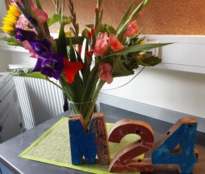 A desk with a vase of colorful flowers and wooden letter blocks spelling "M4". - Hotel M24 (Vechta)