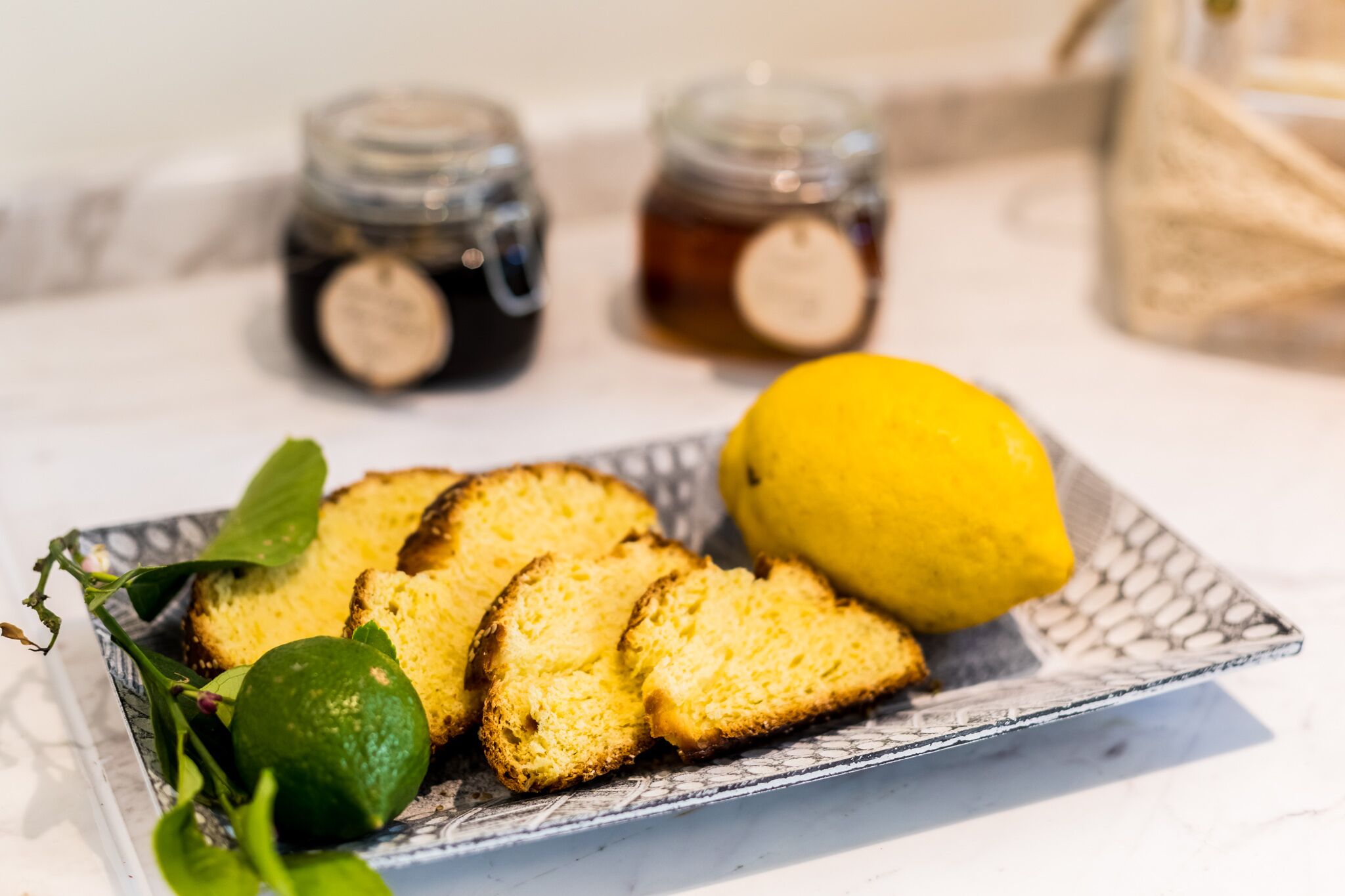 A plate with slices of cake, a lemon, and a lime on a patterned tray.