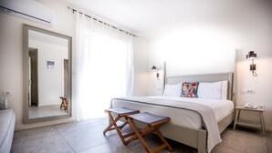 Quarto moderno com cama, mesas de cabeceira, um espelho e vista para um corredor.