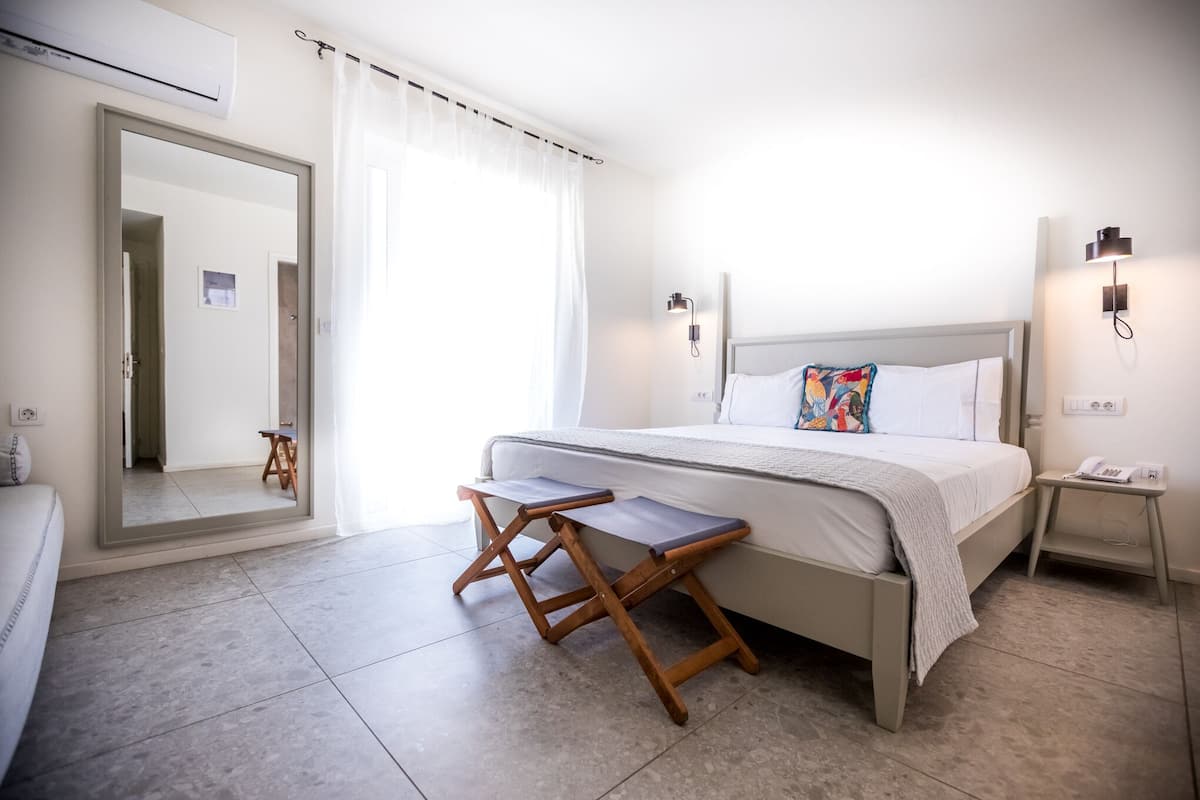 A modern bedroom with a bed, bedside tables, a mirror, and a view of a hallway.
