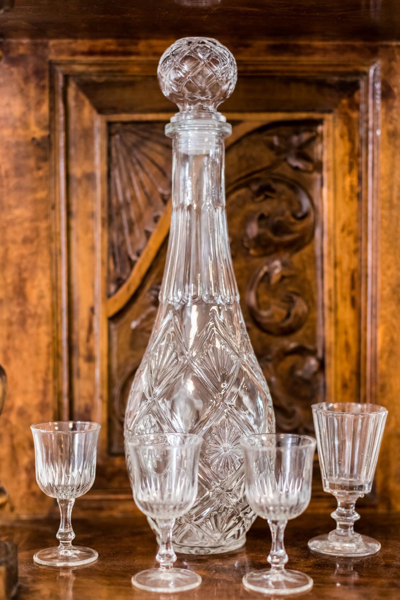 Un decantador de cristal y cuatro vasos a juego sobre una mesa de madera.