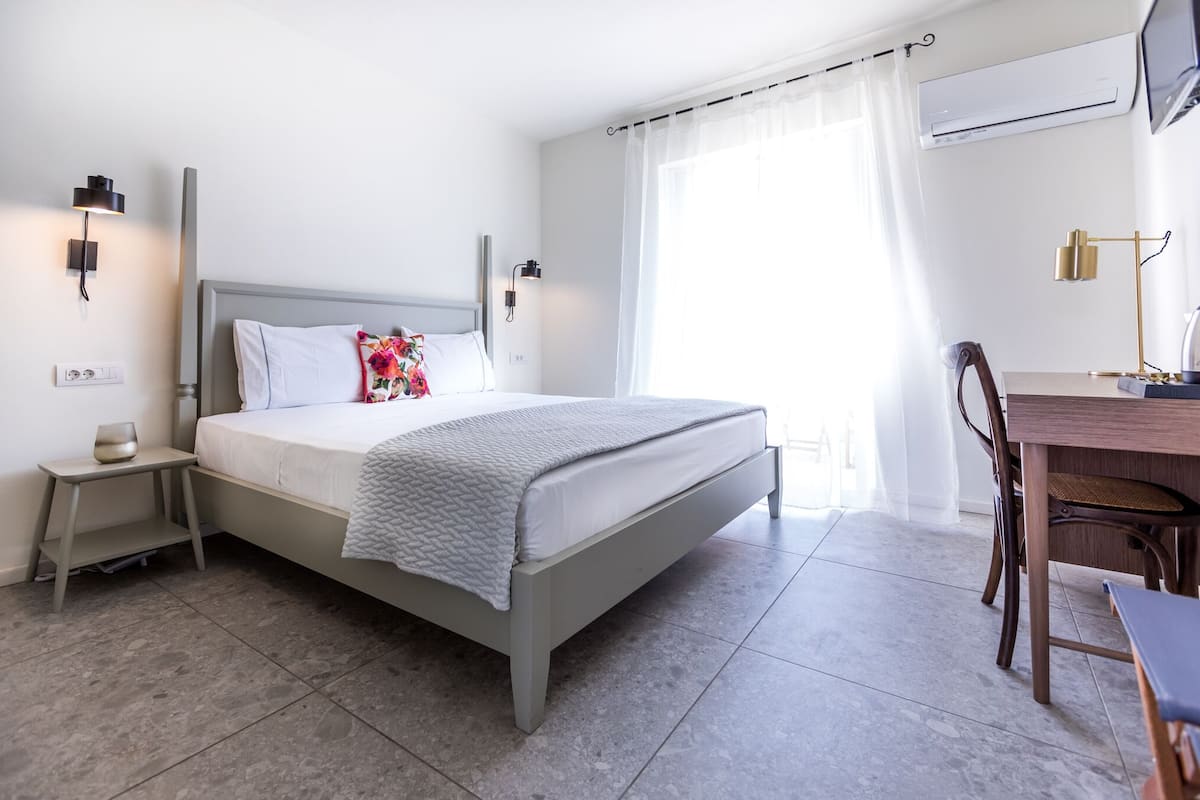 A modern bedroom with a bed, bedside tables, a desk, and a chair.