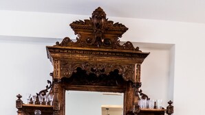 Um armário de madeira com um espelho, copos e uma tigela decorativa.