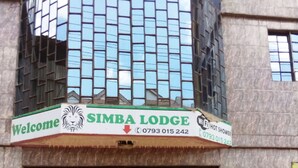 A building with a sign reading "Welcome Simba Lodge" and a contact number. - Simba Lodge (Embu)