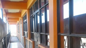 A long corridor with tiled flooring, large windows with metal grilles, and a ceiling with a central light fixture. - Simba Lodge (Embu)