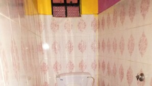 A small bathroom with a toilet, a window, and patterned walls. - Simba Lodge (Embu)