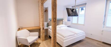 A modern bedroom with a wooden ceiling, a white bed, a desk, and a chair.