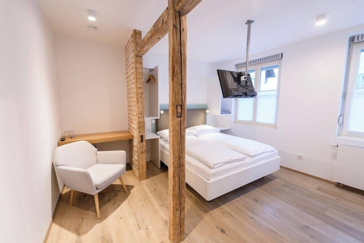 A modern bedroom with a bed, a desk, a chair, and a TV.