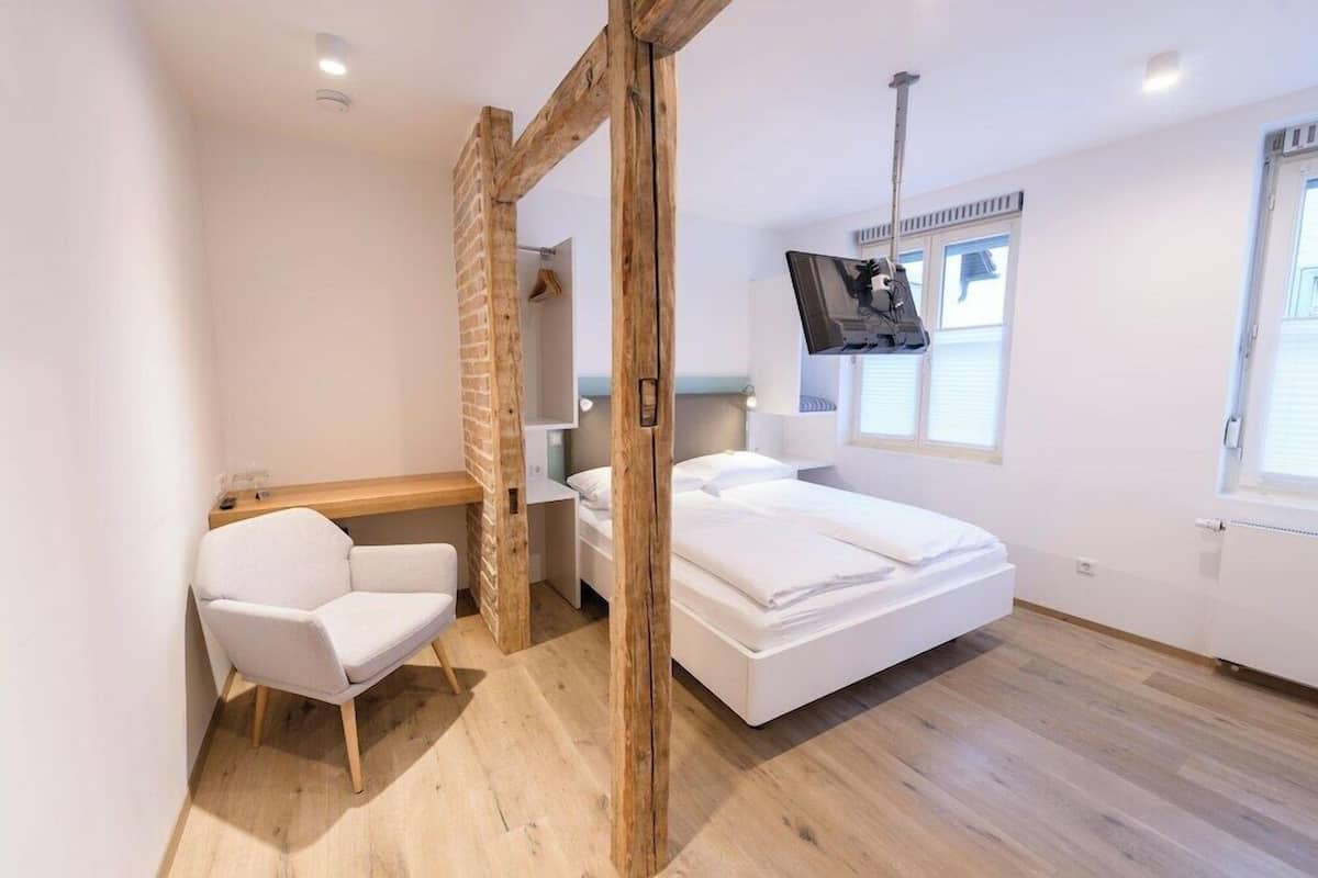 Un dormitorio moderno con cama, escritorio, silla y televisor.