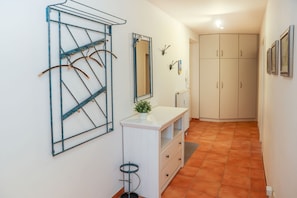 A hallway with a white cabinet, a mirror, and a metal rack.
