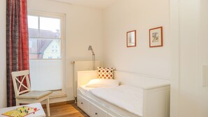 A bedroom with a single bed, a chair, a table with a board game, and a window with curtains. - House Meeresblick WM319 - WM319 (Kühlungsborn)