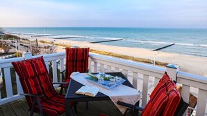 A deck with a table set for two, overlooking a beach with a pier. - House Meeresblick WM319 - WM319 (Kühlungsborn)