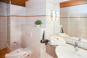 Une salle de bain moderne équipée d’une douche, de toilettes, d’un lavabo et d’un miroir.