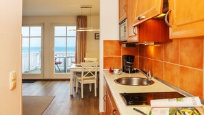 Une cuisine avec vue sur la mer, un coin repas avec une table et des chaises, et une machine à café.