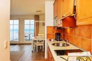 A kitchen with a view to the sea, a dining area with a table and chairs, and a coffee maker.