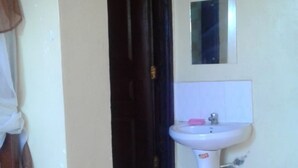 A bathroom with a white sink, a mirror above it, and a dark door leading to another room. - Check Point Guest House (Isinya)