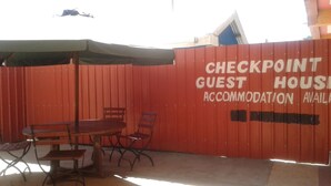 A red fence with a sign that reads "CHECKPOINT GUEST HOUSING ACCOMMODATION AVAILABLE." - Check Point Guest House (Isinya)