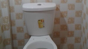 A bathroom with a toilet, patterned tiles, and a warning label on the tank. - Check Point Guest House (Isinya)