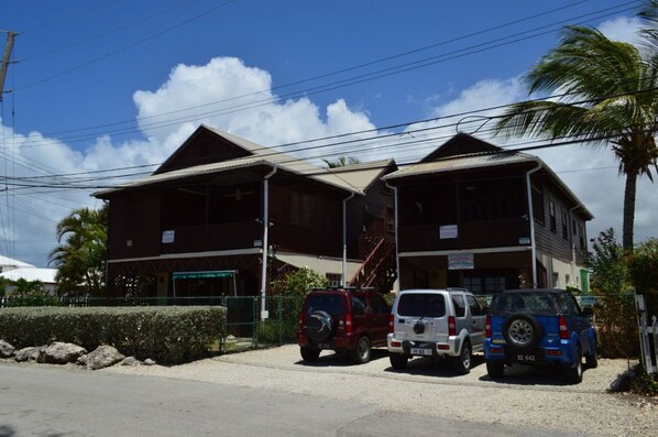 A two-story building with a flat roof and a staircase leading to the upper floor. There are two vehicles parked in front of the building. - Blue Ocean Villa  in Silver Sands (Silver Sands)
