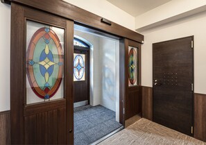 Enter a stylish hotel with a beautifully designed entrance featuring a wooden door and patterned carpet.
