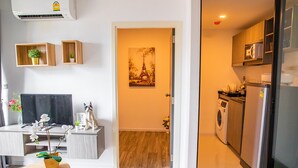 A modern apartment with a kitchen, a dining area with a TV, and a living room with a sofa and decorative plants. - Apartment 450m from BTS with Sky Pool - bkbloft1 (Samut Prakan)