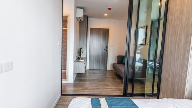 Une chambre d’hôtel moderne équipée d’un lit, d’un canapé, d’un bureau et d’une porte-fenêtre coulissante donnant sur un balcon.