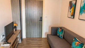 Un salon moderne avec un canapé, un téléviseur et un plancher en bois.