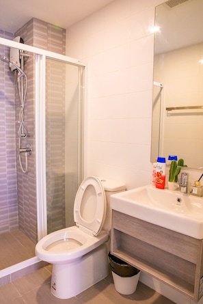 A bathroom with a shower, toilet, sink, and a mirror. - Apartment 450m from BTS with Sky Pool - bkbloft5 (Samut Prakan)