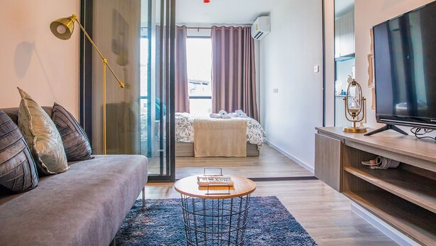 Una sala moderna con un sofá, una mesa de centro, televisor y vistas al dormitorio.