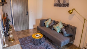 Una sala de estar moderna con un sofá gris, cojines estampados, una mesa redonda de centro y un cuadro de un puente en la pared.