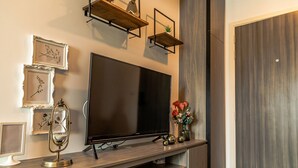 Una sala de estar moderna con un televisor de pantalla plana grande, estantes de madera, adornos y una puerta.