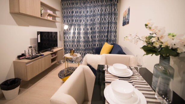 Een moderne woonkamer met een bank, salontafel en eettafel, gedekt voor een maaltijd.